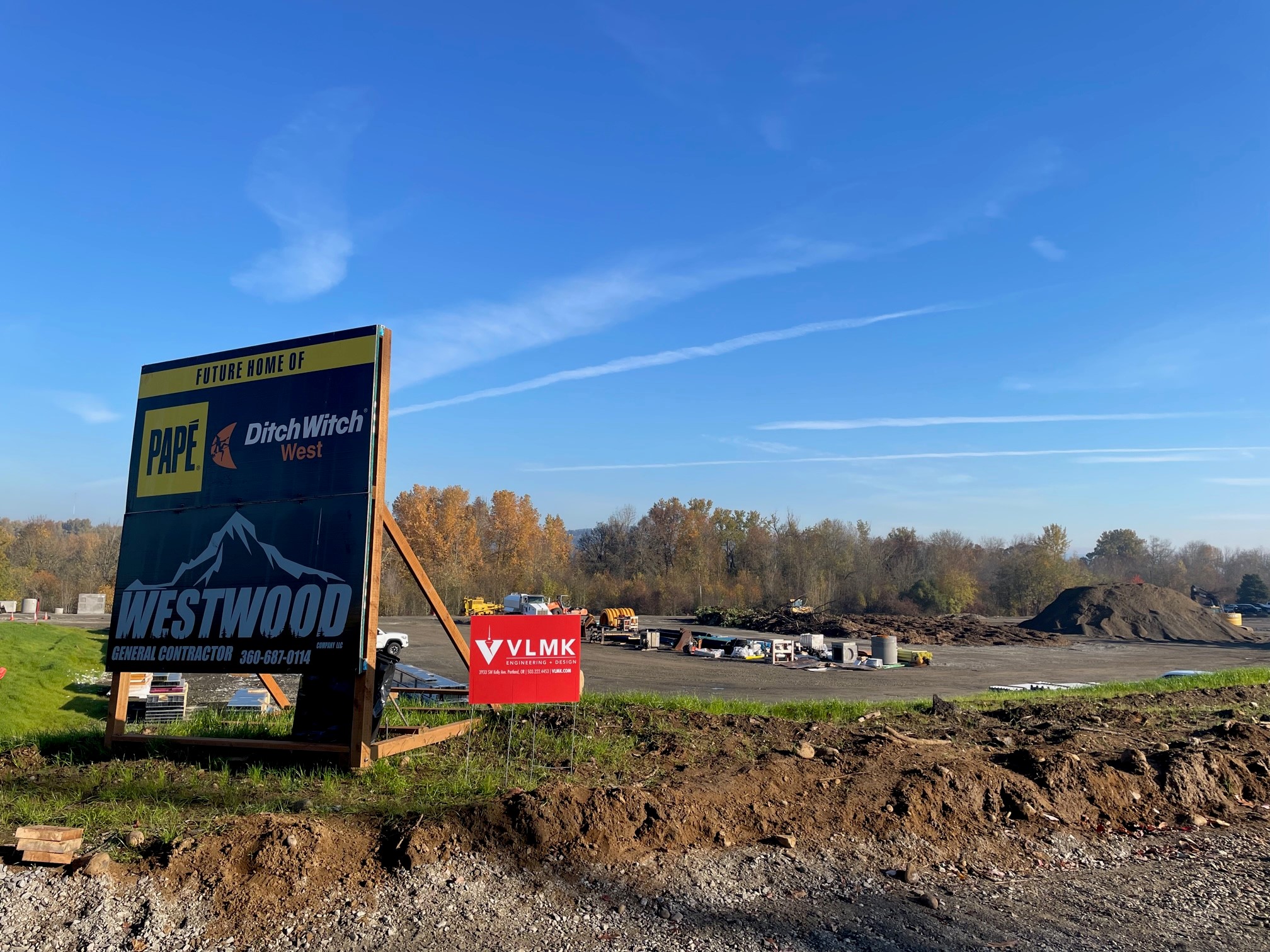 Construction site for Pape Machinery new facility with signs of construction company and designer in front of an empty lot