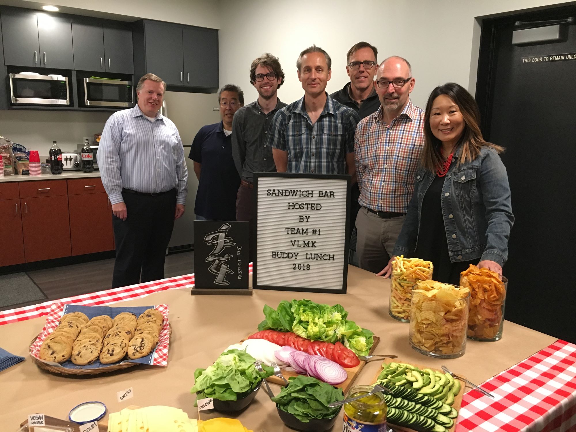 VLMK Buddy Lunches A group of VLMK staff around a lunch table with a sandwich making bar